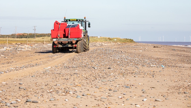 A tractor acting as a furniture removal vehicle on the sand of Spurn Point